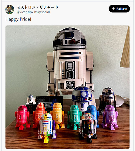 a lineup of various Star Wars astromech droids, from a large, high-end Lego set in the back to a tiny Lego minifigure in the front, with various Funko Pops and Hasbro figures all around. There's a line of rainbow colored droids (solid red, solid orange, solid yellow, etc.) and two in the front that have a white or black body with rainbow colors adorning their various parts