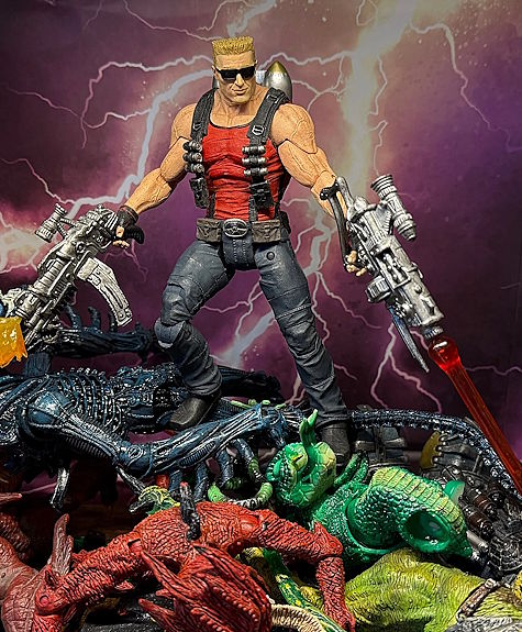 The NECA Duke Nukem action figure standing atop a pile of various alien monster action figures, shooting downward.